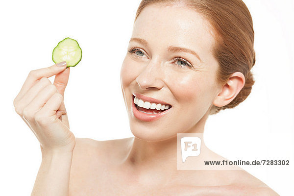 Woman holding up a cucumber slice
