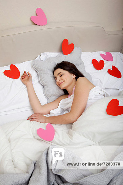 Frau im Bett mit Herzformen auf Bettwäsche