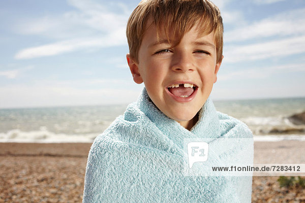 Junge am Strand  in ein Handtuch gewickelt