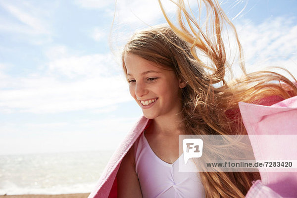 Mädchen am Meer mit Handtuch  Wind im Haar