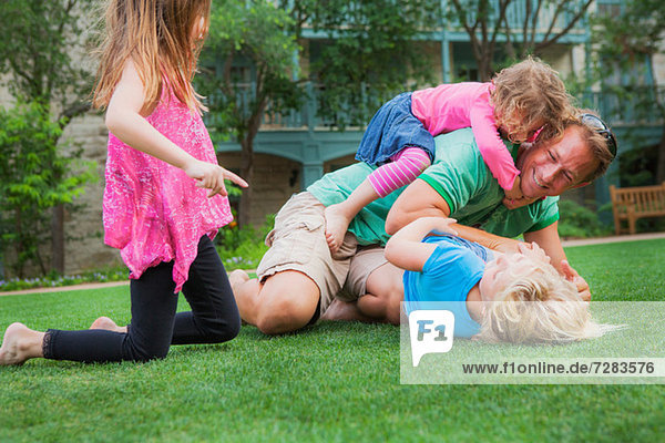 Vater spielt mit seinen Töchtern im Garten