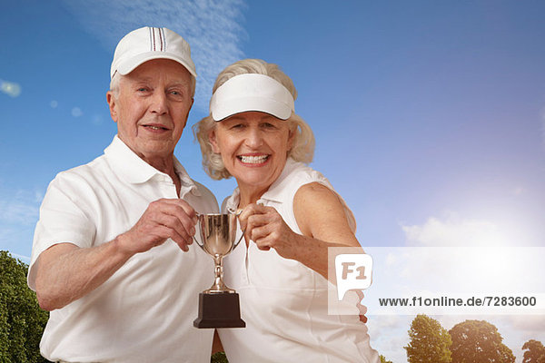 Seniorenpaar mit Tennistrophäe
