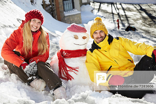 Couple sitting by snowman