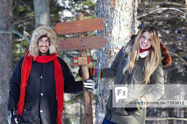 Couple holding wooden sign in forest