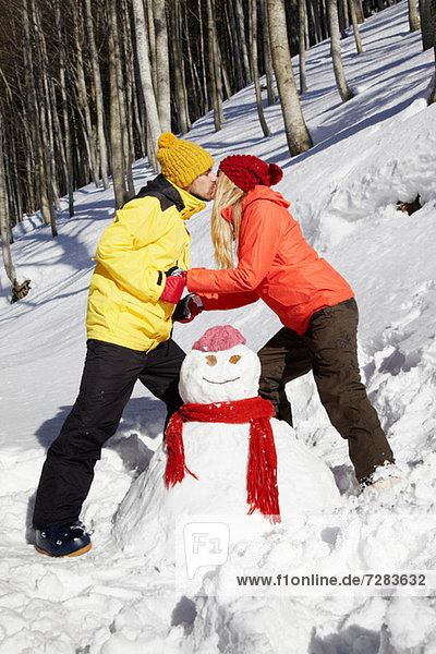 Couple kissing by snowman