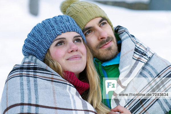 Portrait of couple wearing knit hats  wrapped in blanket