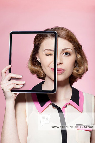 Frau bedeckt ihr halbes Gesicht mit digitalem Tablett