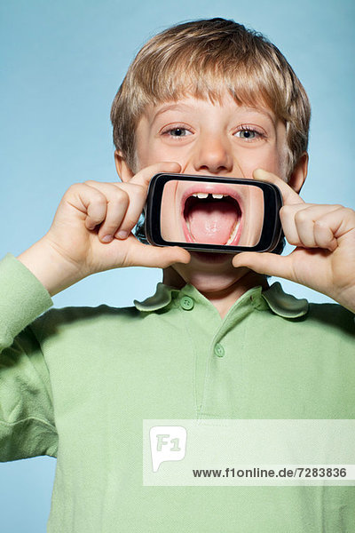 Junge hält Smartphone über den Mund