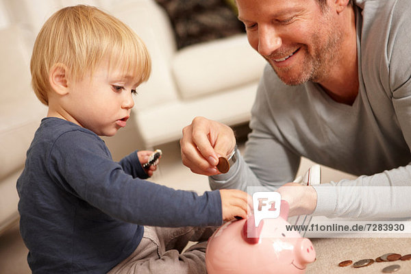 Father and son putting coins in piggy bank