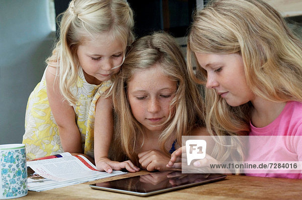 Drei Mädchen beim Betrachten des digitalen Tabletts