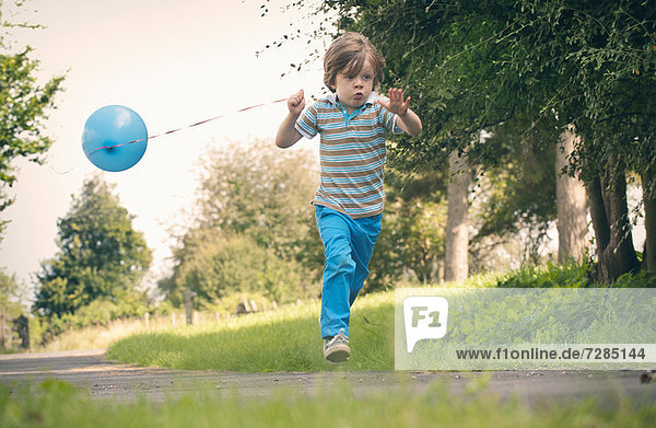 Junge läuft mit Ballon im Freien