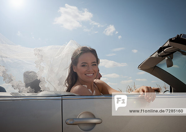 Newlywed couple driving in convertible