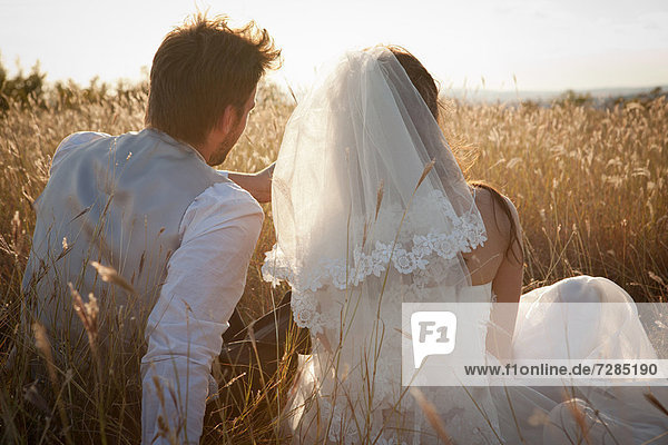 Newlywed couple sitting in tall grass