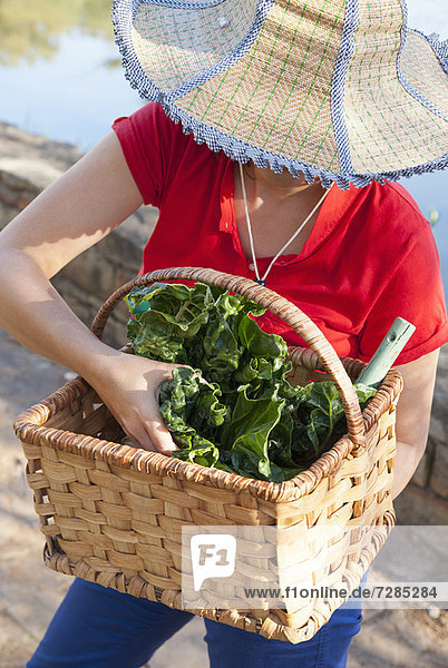Woman carrying basket of vegetables