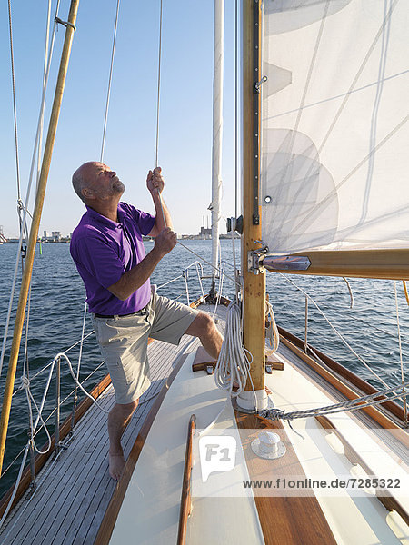 Man adjusting rigging on sailboat