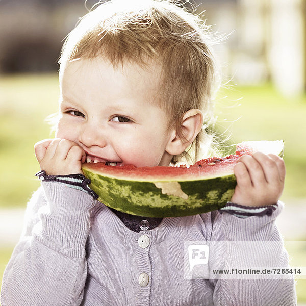 Toddler girl eating watermelon outdoors