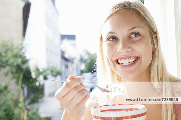 Lächelnde Frau isst Schüssel mit Getreide