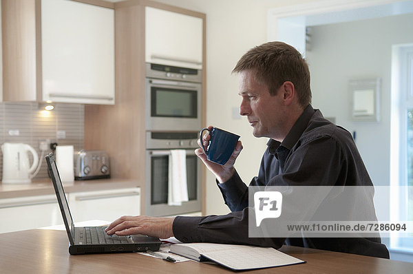 Businessman working on laptop in kitchen