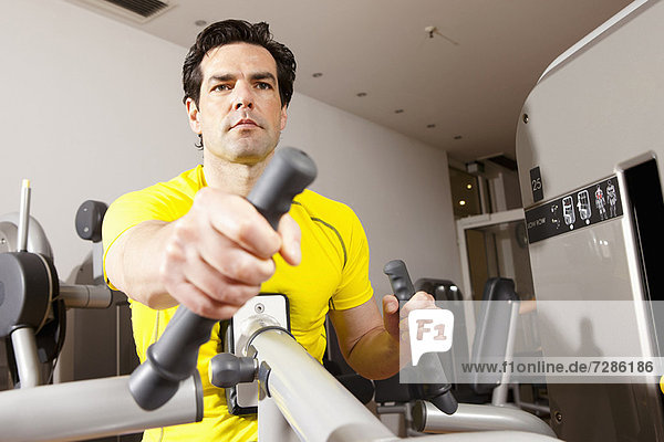 Mann mit Trainingsgeräten im Fitnessstudio