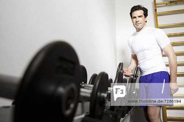 Mann mit freien Gewichten im Fitnessstudio