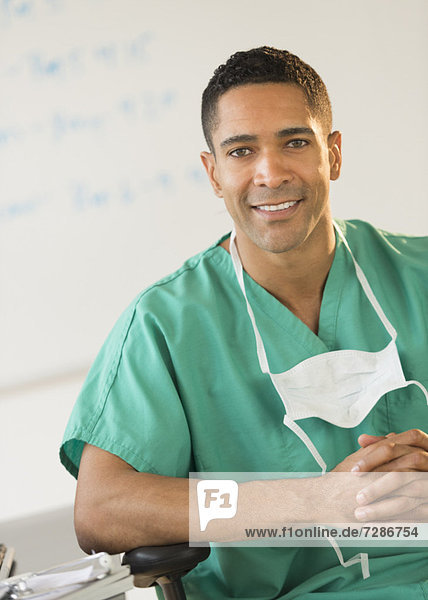 Portrait of male surgeon sitting at desk in hospital