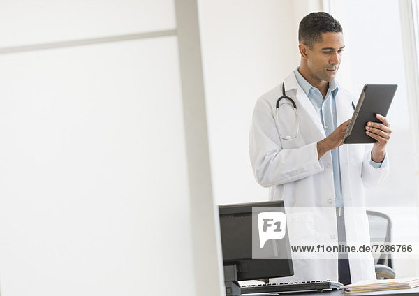 Male doctor using digital tablet in his office
