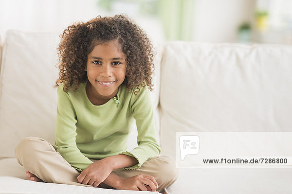 Portrait of smiling girl (6-7) sitting on sofa