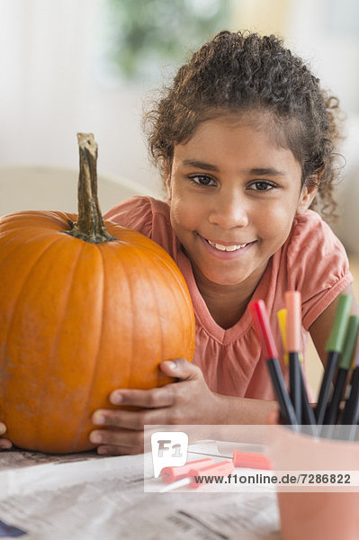 Portrait of girl (6-7) with pumpkin