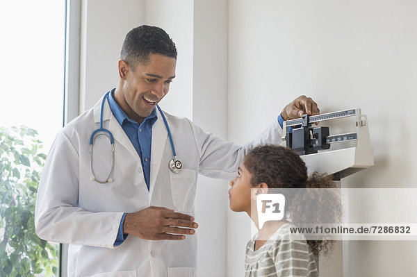 Male doctor examining girl (6-7) in his office