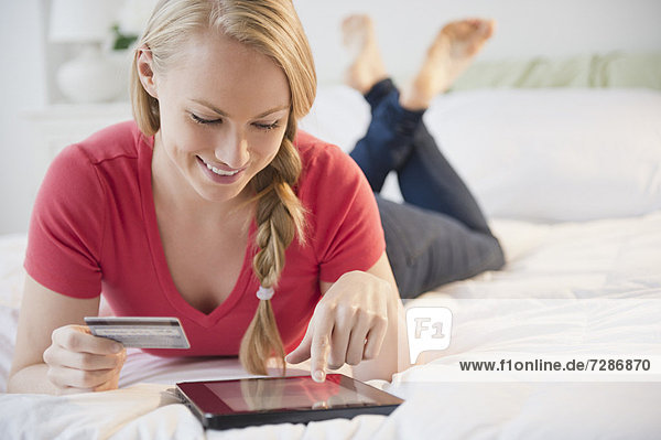 Young woman using digital tablet in bed
