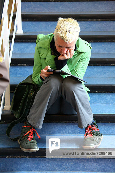 Woman sitting on stairs reading an e-book