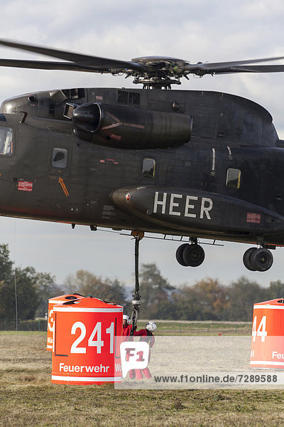 Firefighters hanging a 5000-liter water tank under a CH-53 helicopter of the German armed forces  during an exercise  Laupheim  Baden-Wuerttemberg  Germany  Europe