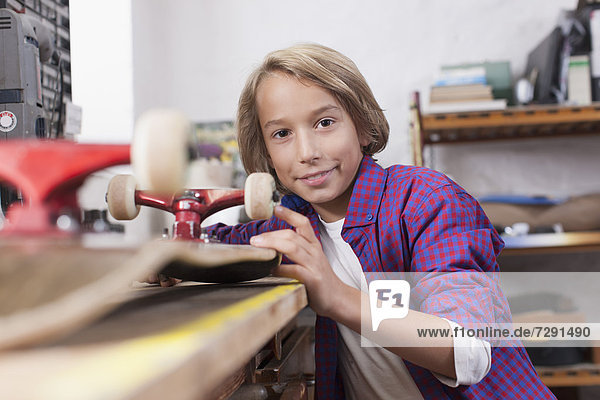 Junge repariert Skateboard,  Portrait
