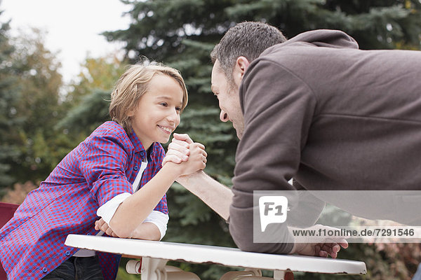 Germany,  Leipzig,  Father and son arm wrestling,  smiling