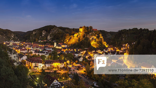 Deutschland  Bayern  Blick auf die Burg Pottenstein auf dem Berg mit der Stadt im Vordergrund bei Nacht