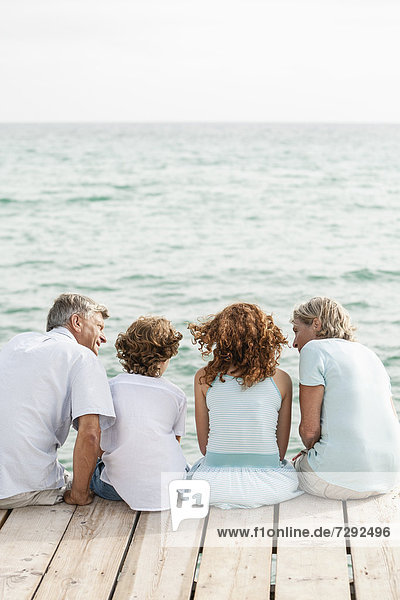 Spain  Grandparents with grandchildren sitting on jetty