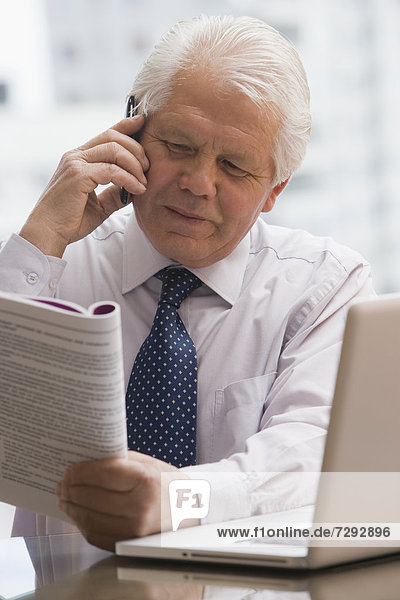 Chilean businessman reading report and talking on cell phone