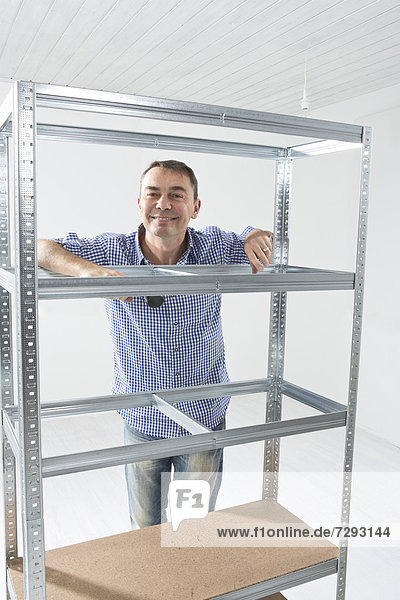 Mature man building shelf  smiling
