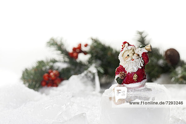 Weihnachtsmann-Figur auf Eiswürfel  Weihnachtsdekoration im Hintergrund