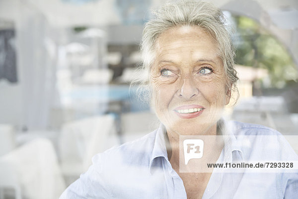 Spain,  Senior woman looking through window,  smiling