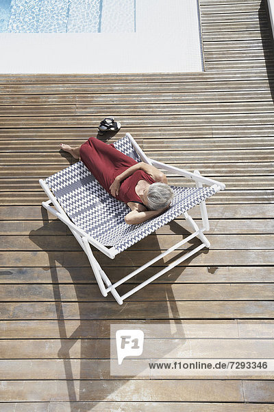 Spanien  Seniorin entspannt auf Liegestuhl am Strand