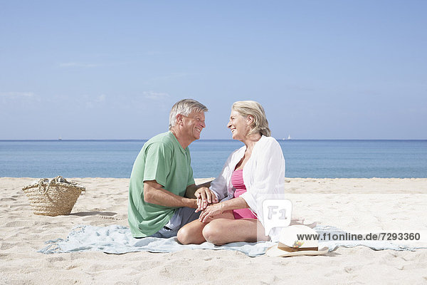 Spain,  Senior couple sitting on beach