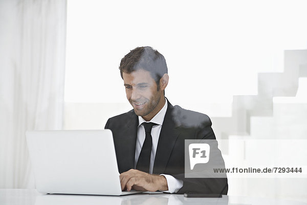 Spain  Businessman using laptop  smiling