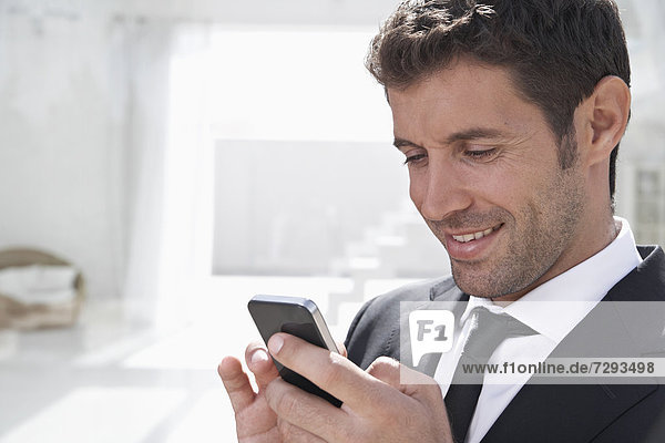 Spain  Businessman using mobile phone  smiling