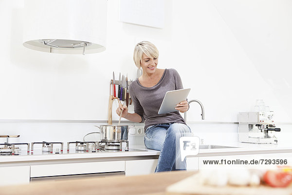 Woman watching digital tablet and preparing food