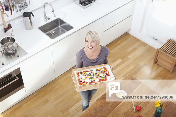 Frau bereitet Pizza in der Küche zu