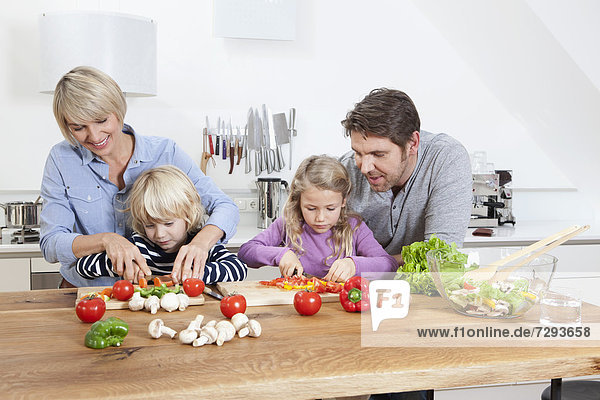 Germany  Bavaria  Munich  Family preparing food in kitchen