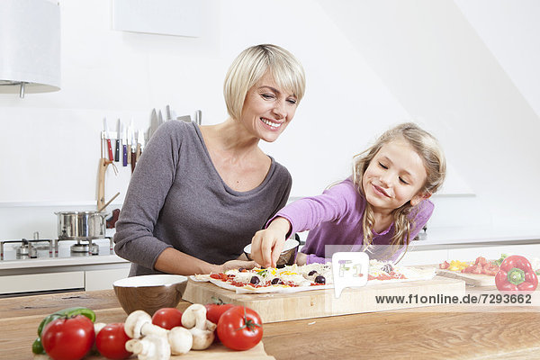 Germany  Bavaria  Munich  Mother and daughter preparing pizza in kitchen