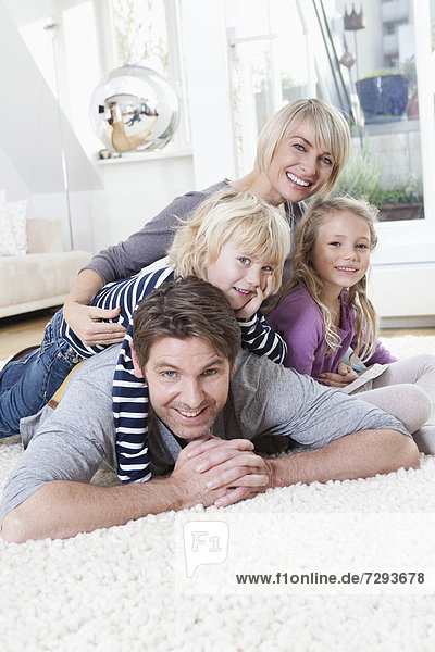 Germany  Bavaria  Munich  Family lying on floor  portrait  smiling