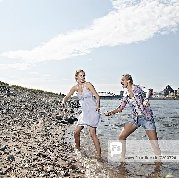 Young women skipping stones in river